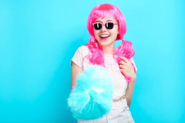 Temizlikçi kadın mavi zemin üzerine mavi toz bezi ile parlak pembe saçlı güzel neşeli gülümseyen kız.