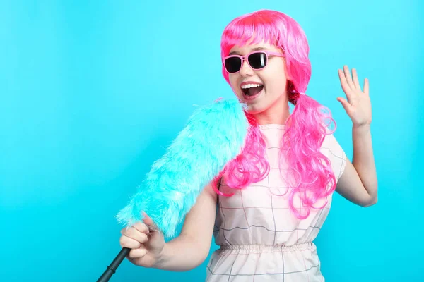 明るいピンク髪 青の背景に青のダスターで清掃の女性の陽気な笑顔美少女 — ストック写真