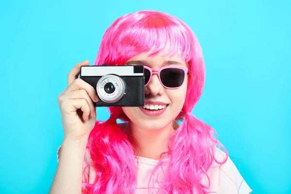 美丽的微笑的女孩与明亮的粉红色的头发与蓝色背景的旧复古相机 — 图库照片