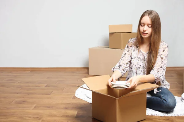 smiling girl puts plates in empty box