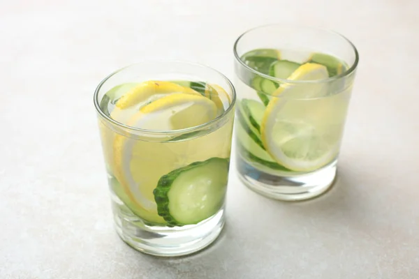 Csésze vízzel, citrommal és uborkával — Stock Fotó
