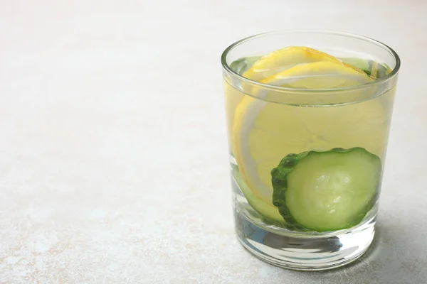 Csésze vízzel, citrommal és uborkával — Stock Fotó
