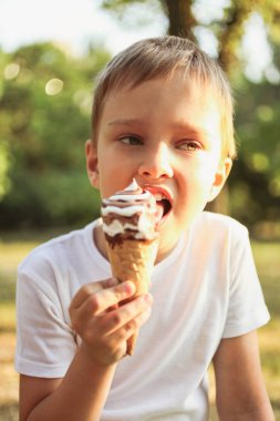 Güneşli yaz gününde parkta serinletici dondurma ile küçük çocuk. Kavram çocukluk, ısı.