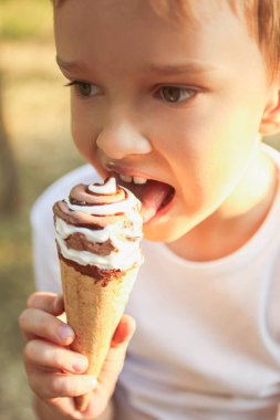 Güneşli yaz gününde parkta serinletici dondurma ile küçük çocuk. Kavram çocukluk, ısı.