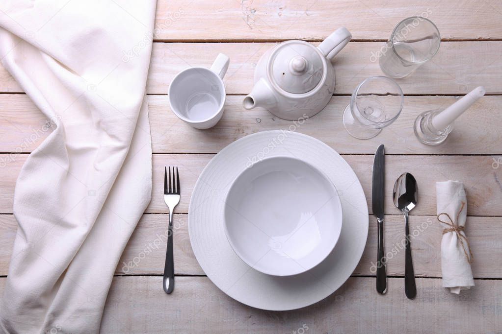 white dishes, cutlery, glasses and candles 