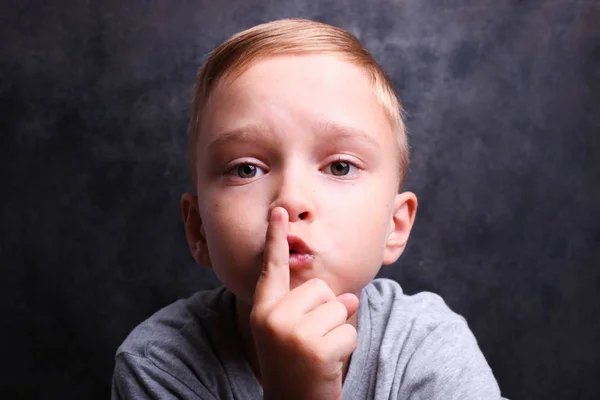 Boy holds his finger near lips — Stock Photo, Image