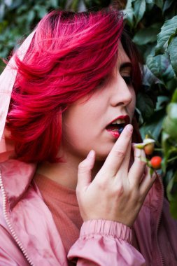 Parlak pembe saçlı kız böğürtlen yer. 