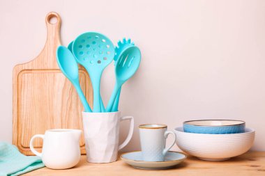 Seramik bir fincanda mavi mutfak aletleri ve nötr bir arkaplanda sofra takımı..