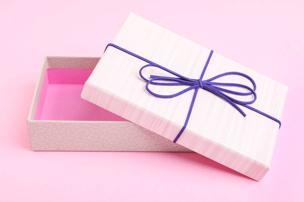 Open beige gift box on a pink background.