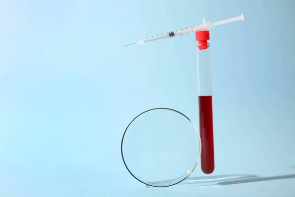 Test tube with blood, Petri dish and insulin syringe on a blue background. Concept analyzes. Balance.