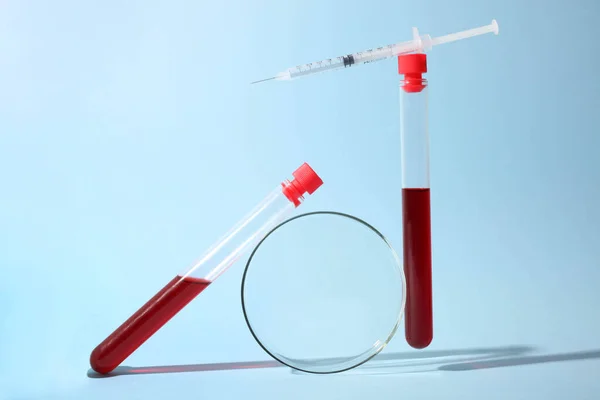 Test tubes with blood, Petri dish and insulin syringe on a blue background. Concept analyzes. Balance.