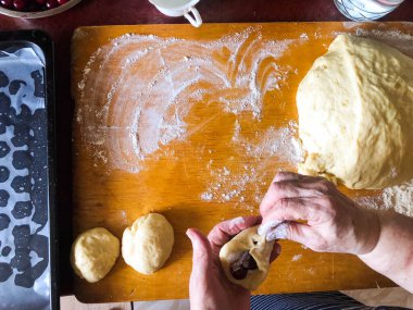 Kadınların elleri hamurdan kirazlarla turta yontuyor. Kızarmış turta pişiriyorum..