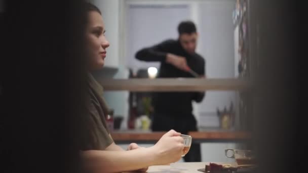 Cafés e restaurantes, aconchego, comunicação, conceito de parentes - duas jovens irmãs conversando bebem chá com doces sentados em vestidos na mesa da cozinha em casa à noite. Mulheres conversando . — Vídeo de Stock
