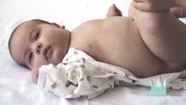 Kojenec, mateřství, vývoj, dětství, trénink, pediatrie, medicína a zdraví koncept - close-up nahý novorozenec lži probudí maminka dává dítě v obleku. na bílém pozadí. — Stock video