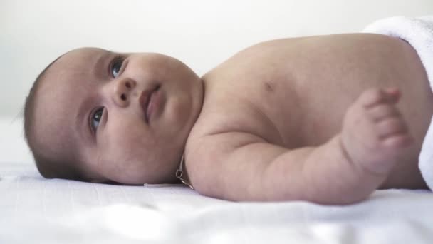 Infant, development, childhood, training, pediatrics, medicine and health concept - close-up naked newborn baby lies wakes up on bed showing different grimaces and emotions on white background — Stock Video