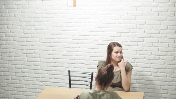 Cafés e restaurantes, aconchego, comunicação, conceito de parentes - duas jovens irmãs conversando bebem chá com doces sentados em vestidos na mesa da cozinha em casa à noite. Mulheres conversando . — Vídeo de Stock