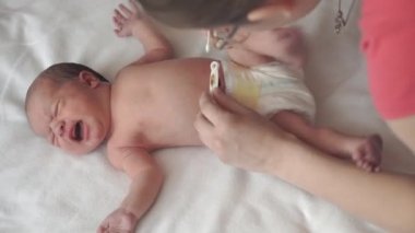 Bebeklik, çocukluk, annelik, aile, hijyen, tıp ve sağlık konsepti - yakın plan anne karın pamuğu hijyenik çubuğu yeni doğan bebeğin beyaz arka planda beyaz arka planda üst görünümü ile ilgilenir
