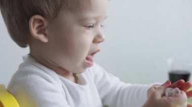 Sarışın bir çocuk ıslak peçeteyle yumurta ve temiz eller boyuyor. Paskalya için hazırlanıyor. Kapalı mekanda ellerle resim yapmak. 3 yaşından küçük çocuklar için yaratıcı bir gelişme. Eğitim, evde çizim yaparken
