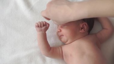 bebek bezi, çocukluk, annelik, hijyen, ilaç ve sağlık konsepti - kadın anneler yeni doğmuş çıplak bebeğin yüzünü pamuk bezle siliyor ve sırtında tıbbi klipsle klempler takıyor.