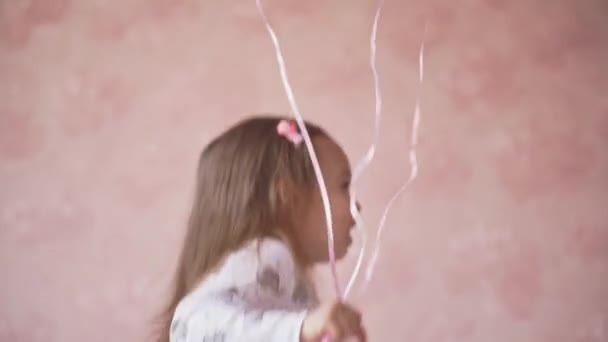 Kinderen, feest, verjaardag, grote gezinnen, spelletjes en entertainment concept - Little Girl Looks Out From Behind Ballon and Laughs Happily. close-up portret van kind spelen op roze achtergrond — Stockvideo