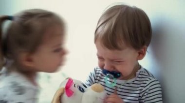 Çocukluk, aile, ceza, yetiştirme, karantina, kendini tecrit, histerik kavramlar. Ağlamak için meme ucu olan küçük üzgün bebek. Kız kardeş acıması, küçük kardeşi öp. Kız ağlayan çocuğu öpüyor.