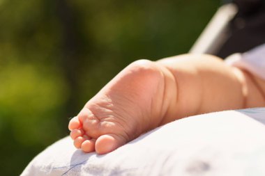 Yeni doğmuş bir bebek güneşte güneşleniyor. Sağlık, tedavi, dermatoloji, çocukluk, yaz, dinlenme, yürüyüş. Küçük bebek ayağı. Yeni doğan sıcak ve parlak havada dışarıda uyur. Hava banyosu. Boşluğu kopyala