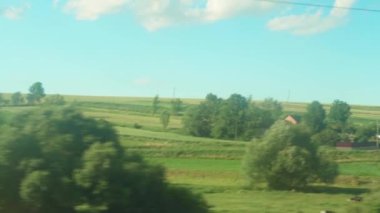 Ulaşım, seyahat, yol, demiryolu, manzara, çiftleşme konsepti - bulutlu aydınlık bir günde doğanın ve ormanın güzel çayırlarının manzarası üzerinde hız treninin penceresinden manzara