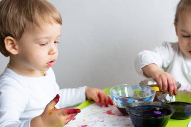 Mutlu Paskalyalar. Çocuklar yumurta boyadı. İki çocuk Paskalya için hazırlanıyor. Boyalı el. Parmak boyası. Sanat ve zanaat konsepti. Geleneksel bahar tatili yemekleri