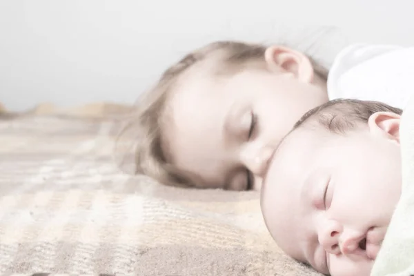 Close-up zicht op twee kinderen, pasgeboren baby, drie jaar oud meisje slapen samen op beige bed. Zusters slapen op de bank thuis. Jeugd, kindertijd, familie, slaap, rust, liefde concept. kopieerruimte — Stockfoto