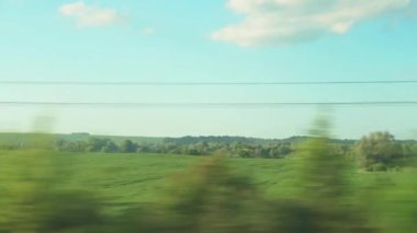 Ulaşım, seyahat, yol, demiryolu, manzara, çiftleşme konsepti - bulutlu aydınlık bir günde doğanın ve ormanın güzel çayırlarının manzarası üzerinde hız treninin penceresinden manzara