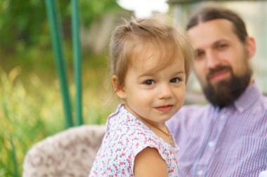 Küçük çocuklu genç baba yazın dinleniyor. Baba ailesiyle vakit geçiriyor. Mutlu gülümseyen kız, babamla birlikte Garden 'da. Çocuk hayatın neşesi. Reşit olmayan birinin duyguları. çocukluk, babalık