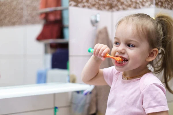 Washing hands with soap under the faucet with water. Little girl brushing teeth with toothpaste and brush in brown bathroom.Hygiene, coronavirus, childhood, upbringing, motherhood concept. — Stock Photo, Image