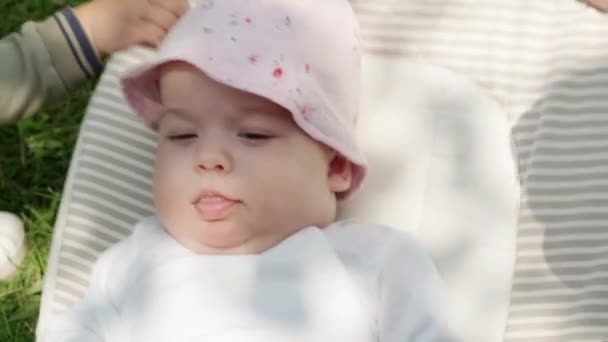 婴儿期 医药与健康概念 躺在绿草摇椅背景下五个月醒着的女婴的特写 — 图库视频影像