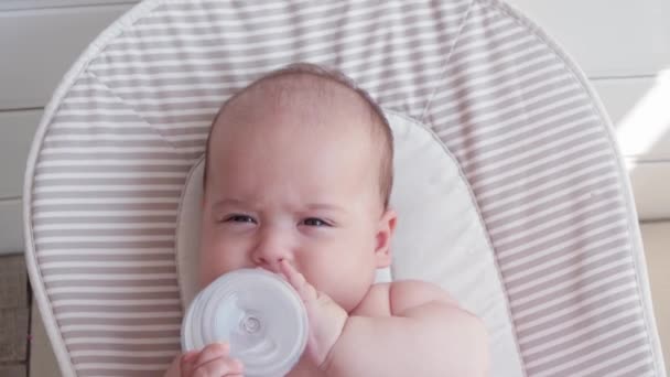 유아기 의학과 갓난아기의 개월된 아기가 물병에서 마시며 흔들의자에 모습을 — 비디오