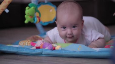 Bebeklik, çocukluk, gelişme, yaz tatili, yaşam tarzı konsepti - 5 aylık paspasın üzerinde yatıp karnını oyuncaklarla doyuran mutlu, yeni doğmuş çocuğun kapanışı