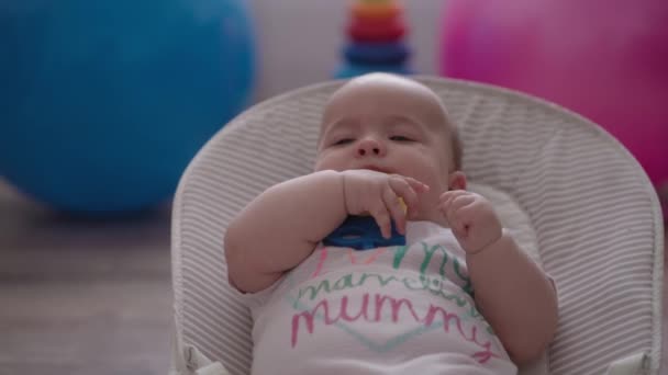 婴儿期 医药与健康概念 五个月前醒着的女婴躺在摇椅上与玩具枪的特写 — 图库视频影像