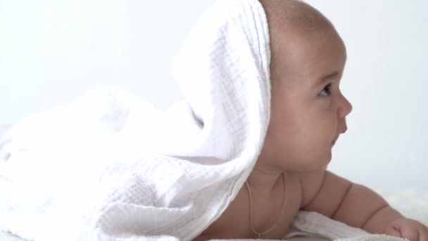 Kindheit, Tagesablauf, Hygiene-Konzepte für Säuglinge - Close-up Happy-Kids-Handtuch auf weißem Hintergrund nach dem Baden. Neugeborenes nach der Dusche auf dem Bauch im Bett. Babywachzeit vor dem Schlafengehen — Stockvideo