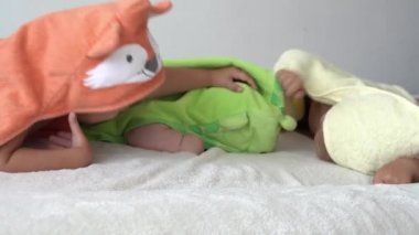 Çocukluk, günlük rutin, hijyen kavramları, banyo yaptıktan sonra beyaz arka planda bornozlu üç mutlu çocuk. Kız ve yeni doğan bebek duştan sonra karın üstü yatıyorlar. Yatmadan önce havlusu olan İrlandalı ikizler