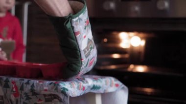 Xmas, kış, yeni yıl, kutlama, aile, fırın, hazırlık, yemek konsepti - Genç anne, Noel 'de dekore edilmiş küçük oğlu fırının yanında dururken hamur işleri hazırlıyor