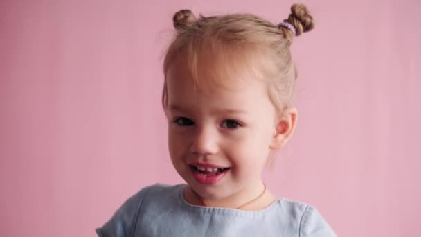 Childhood, celebration, birthday, games concept - close-up little blond-haired girl play hide and seek and showing different emotions makes peekaboo covering eyes with hands on pink solid background — Stock Video