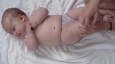 Tıp, sağlık, masumiyet, pediatri, bebek konseptleri - anne elleri yeni doğan çocuğuna bacak, ayak, parmak ve egzersiz, karın veya göğüs masajı yapar.