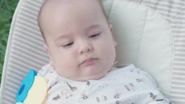 bebeklik, çocukluk, gelişme, yaz tatili, tıp ve sağlık konsepti - Beş aylık uyanık bebek bebek portresi yeşil çimenlerin arka planında sallanan sandalyede yatıyor