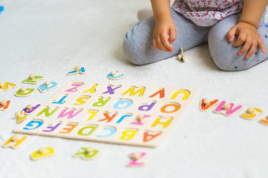 Okula hazırlanıyorum. En küçükler için eğitim. Anaokulunda anaokulu eğitimi. Küçük çocuk evde alfabeden yapboz yapıyor. Çocuklar için renkli İngiliz alfabesi. Gemide bulmacalar