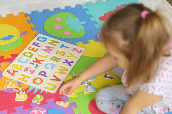 Preparándose para la escuela. Educación para los más jóvenes. Educación preescolar en jardines de infancia. niño hace rompecabezas fuera del alfabeto en el suelo en casa.Color Inglés Alfabeto para niños. rompecabezas a bordo —  Fotos de Stock