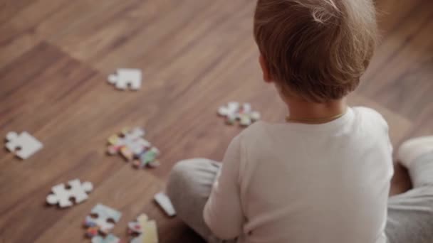 精神发展的概念 一个可爱的两岁小男孩在家里被隔离的明亮的阳光明媚的育婴室的白床上做拼图 小孩在室内自学 — 图库视频影像