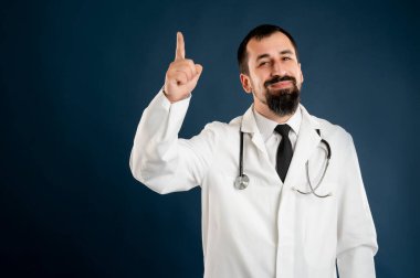 Tıp üniformalı, steteskoplu bir erkek doktorun portresi mavi izole bir arka planda poz veren bir fikirle ortaya çıktı..