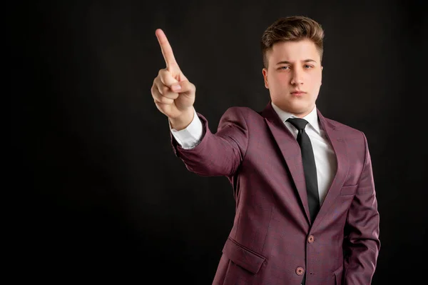 Law student with blond hair dressed in burgundy jacket, white shirt and black tie showing no with his finger posing on isolated black background with copy space advertising area