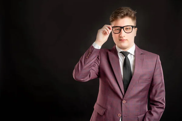 Portrait of law student with blond hair wearing glasses dressed in burgundy jacket, white shirt and black tie posing on isolated background with copy space advertising area