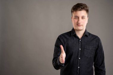 Gri arka planda izole edilmiş siyah gömlekli, şık ve çekici bir adamın portresi.