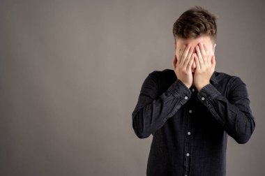 Gri arka planda izole edilmiş, fotokopi çekilen, siyah gömlekli, gözleri kör eden, ciddi ve şık bir adamın portresi.